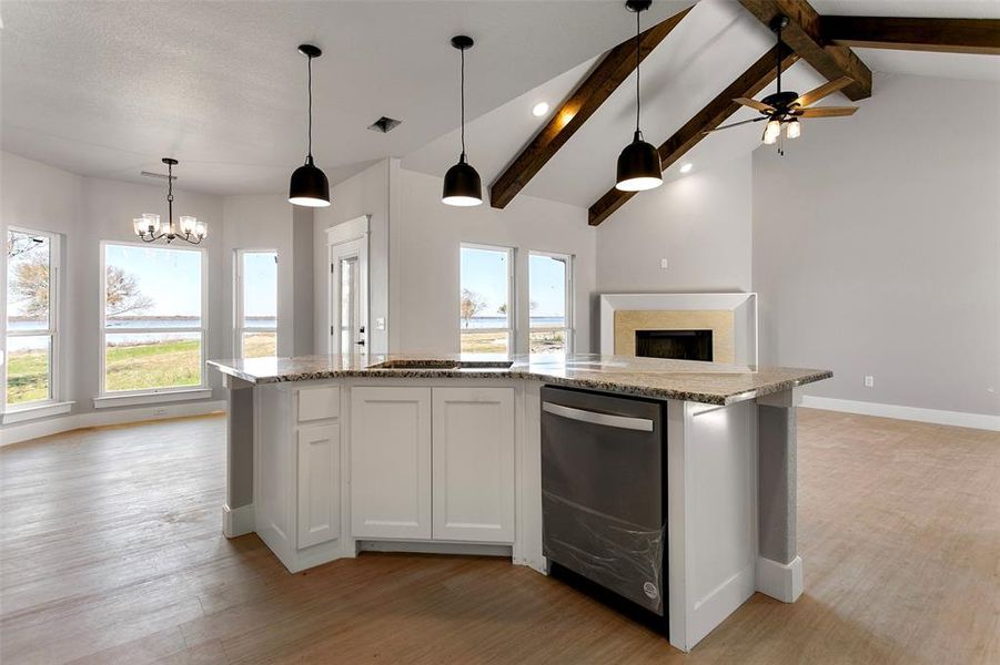 Kitchen featuring vaulted ceiling with beams, white cabinetry, a healthy amount of sunlight, and light wood-type flooring