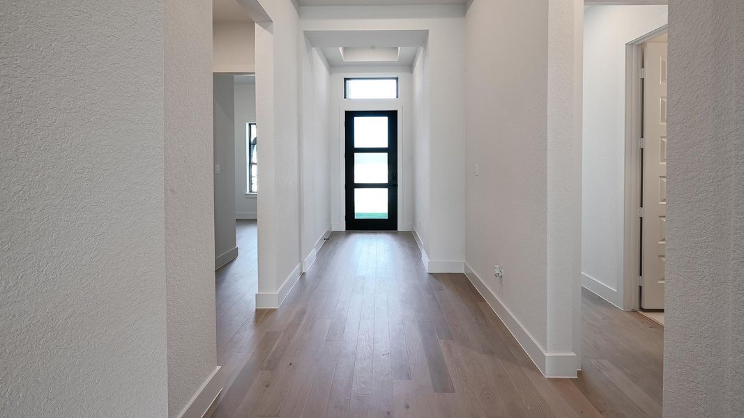Hallway featuring a textured wall and light wood-style flooring Hallway featuring a textured wall and light wood-style flooring