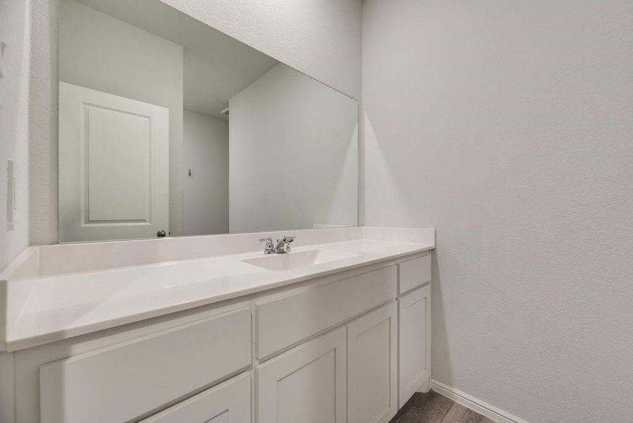 Bathroom vanity with an integrated white countertop and sink, white cabinetry, and a large wall-mounted mirror