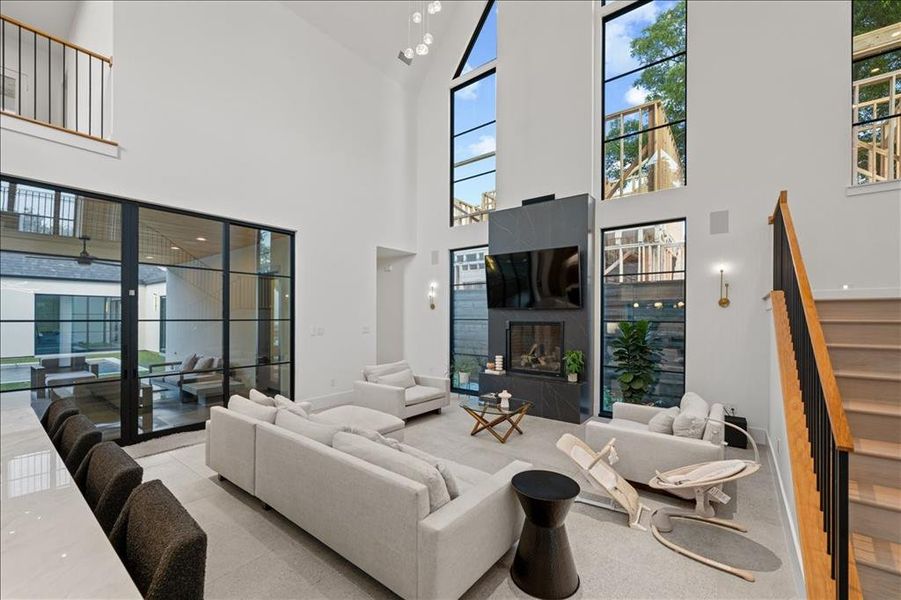 Living area with stairs, a glass covered fireplace, and a towering ceiling