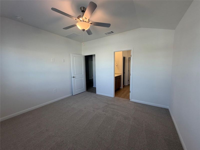 Unfurnished bedroom with carpet, a ceiling fan, vaulted ceiling, and ensuite bath Unfurnished bedroom with carpet, a ceiling fan, vaulted ceiling, and ensuite bath