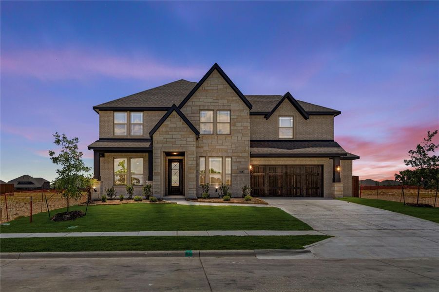 Two-story home with stone and brick exterior, two-car garage, and green front lawn at dusk Two-story home with stone and brick exterior, two-car garage, and green front lawn at dusk