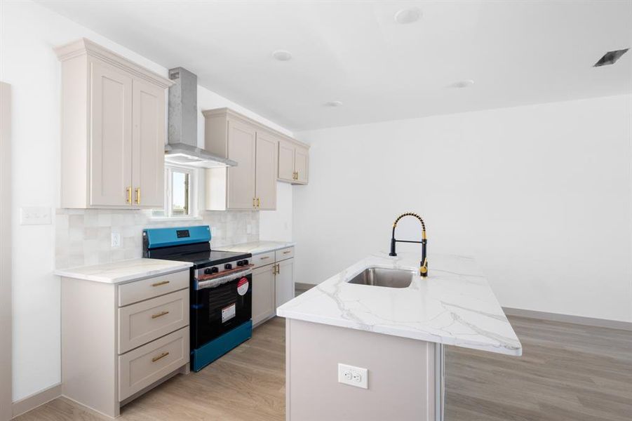 Kitchen featuring a sink, stainless steel range with electric stovetop, wall chimney exhaust hood, backsplash, and a peninsula Kitchen featuring a sink, stainless steel range with electric stovetop, wall chimney exhaust hood, backsplash, and a peninsula