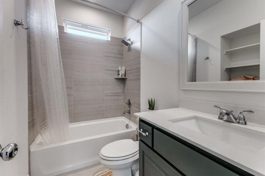 Bathroom with vanity, shower / tub combo with curtain, and a textured wall