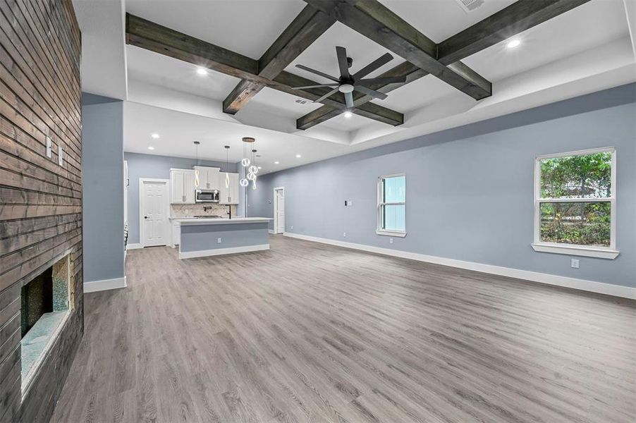 Unfurnished living room with hardwood / wood-style flooring, a brick fireplace, coffered ceiling, ceiling fan, and beam ceiling