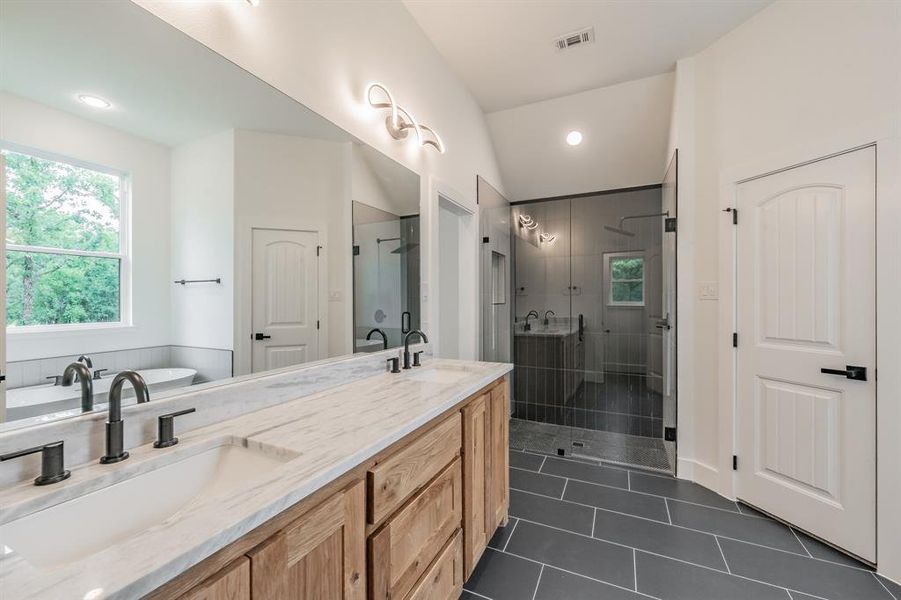 Bathroom featuring a shower stall, tile patterned floors, double vanity, a freestanding tub, and recessed lighting