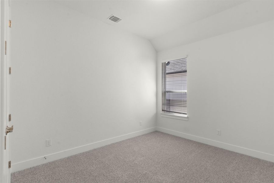Empty room with carpet flooring and vaulted ceiling