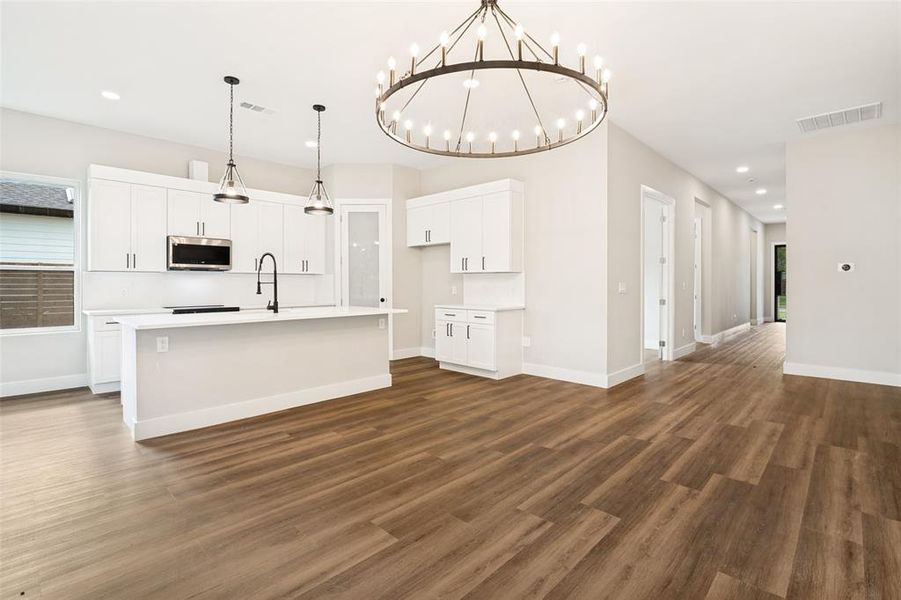 Open concept living area featuring wood-finish flooring and a contemporary chandelier