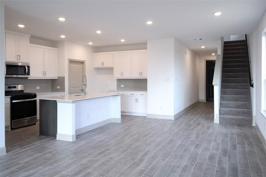 Kitchen with light wood finished floors, recessed lighting, appliances with stainless steel finishes, and a sink