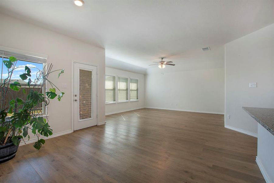 Unfurnished living room with ceiling fan, dark hardwood / wood-style floors, and plenty of natural light