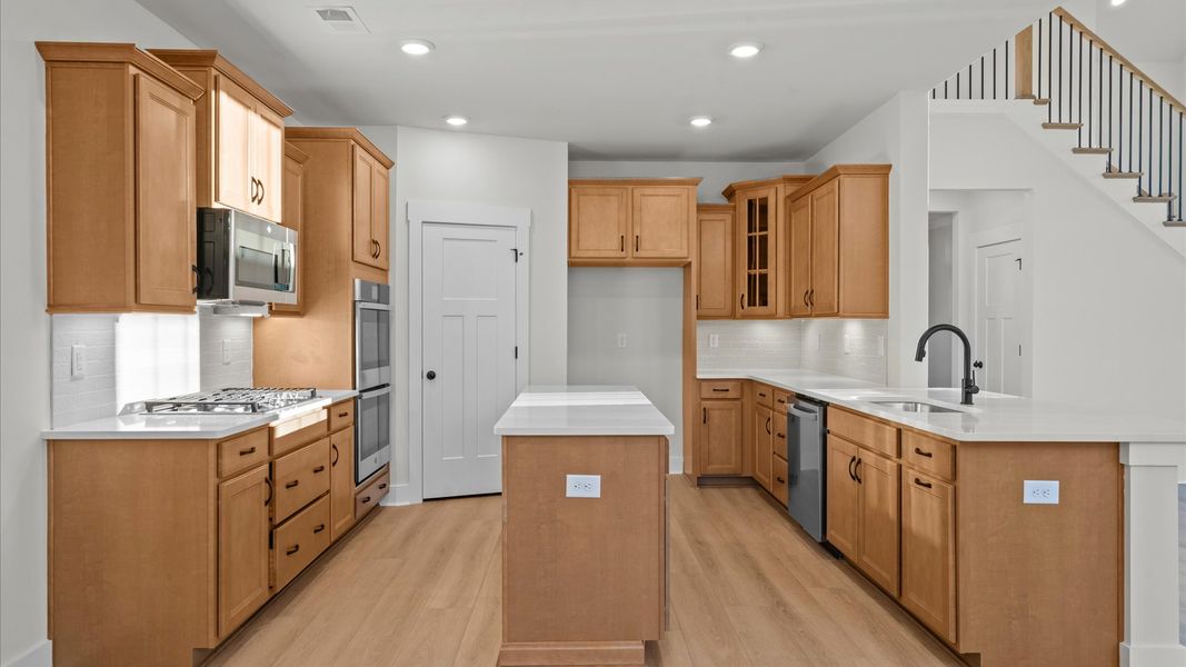 Highly skilled design choices create a clean, open kitchen with a central island