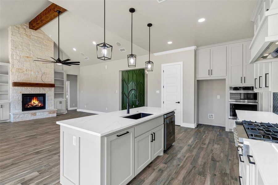 Kitchen with sink, a center island with sink, white cabinets, and light stone counters