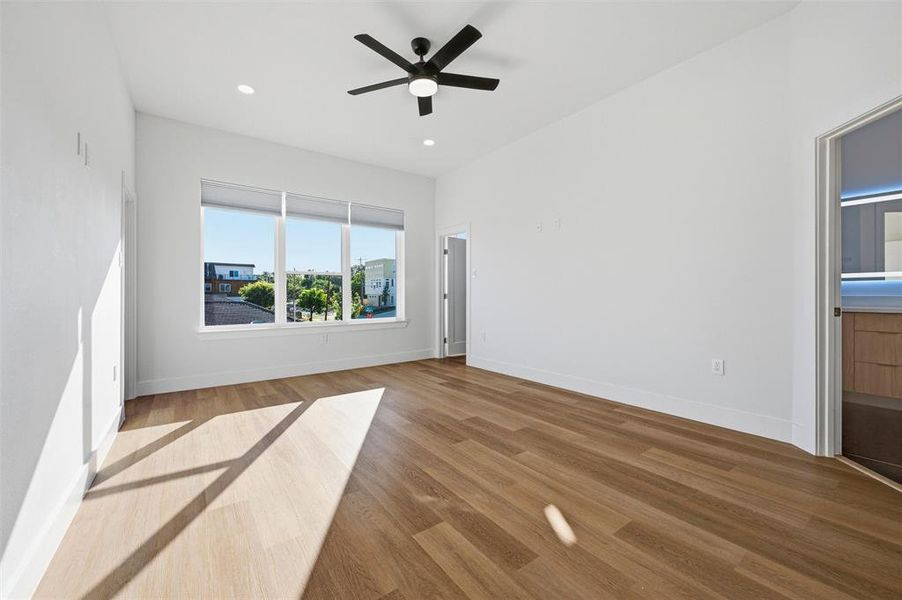 Primary Bedroom features recessed lighting and ceiling fan with light fixture. Large window provides
abundant natural light and neighborhood views. Doorway connects directly to the ensuite bathroom. Vinyl flooring extends throughout.