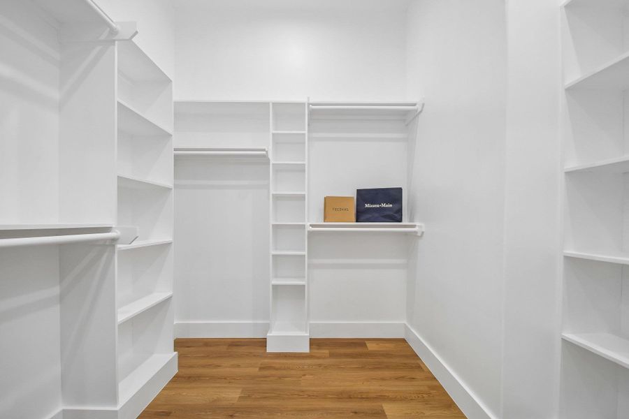 Rich wood flooring contrasts with clean white custom shelving in this organized walk-in closet. Rich wood flooring contrasts with clean white custom shelving in this organized walk-in closet.