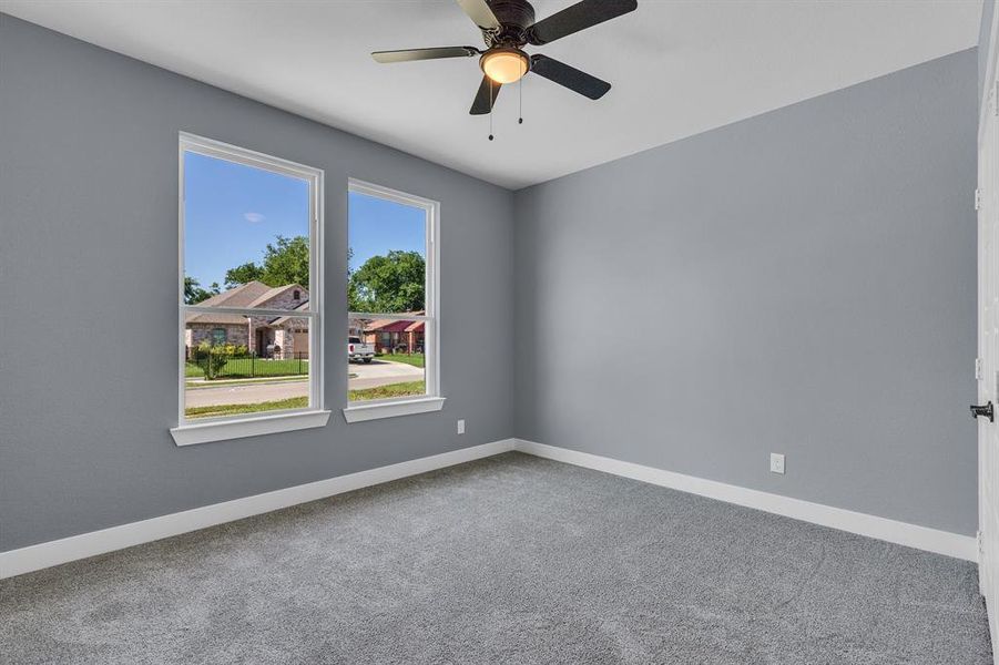 Carpeted spare room featuring ceiling fan