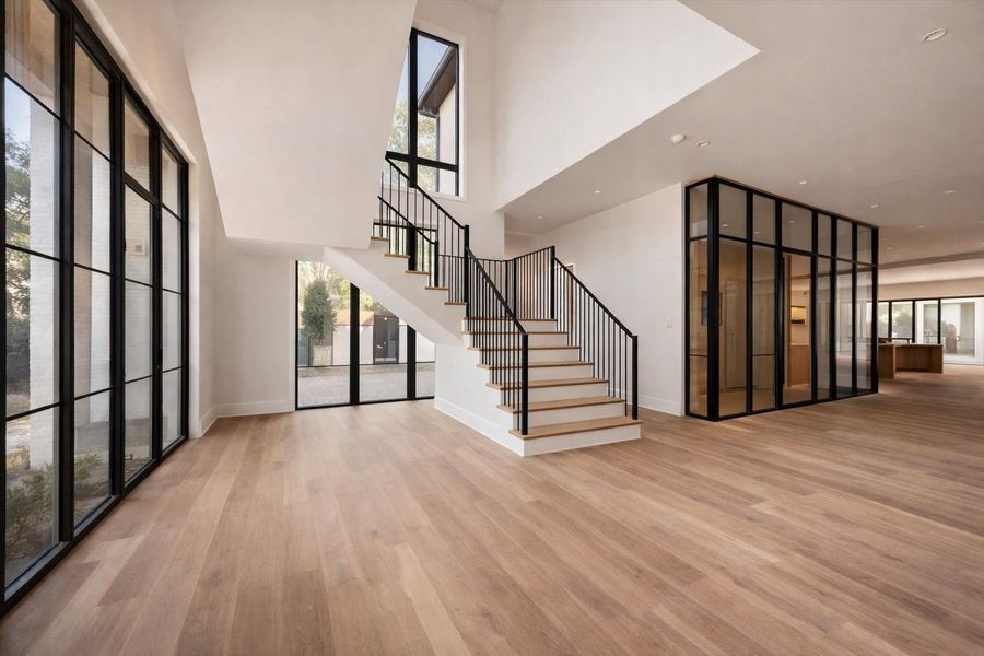 Rendering: Grand staircase entry featuring modern iron railings and expansive floor to ceiling windows that flood the space with natural light.
