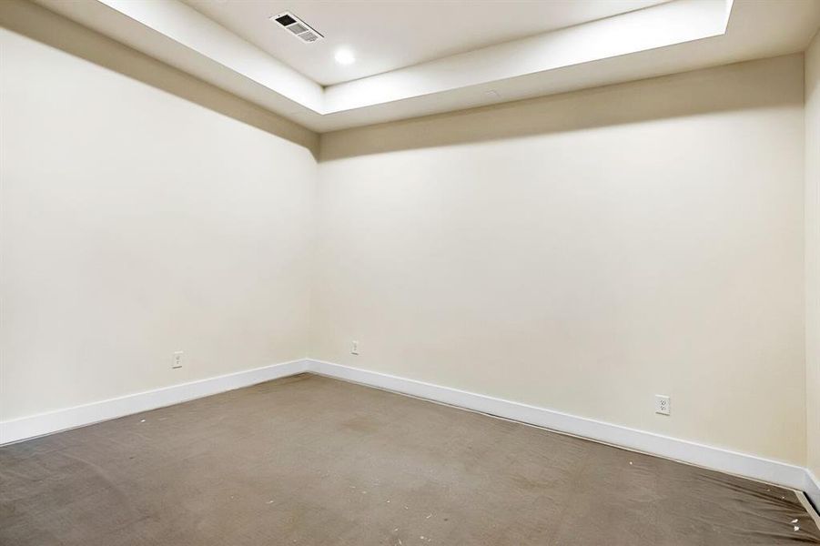 Unfurnished room with concrete flooring, a raised ceiling, and recessed lighting Unfurnished room with concrete flooring, a raised ceiling, and recessed lighting