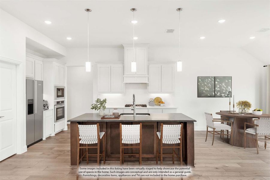 White kitchen with large dark wood island, three pendant lights, and stainless steel appliances, open to dining area