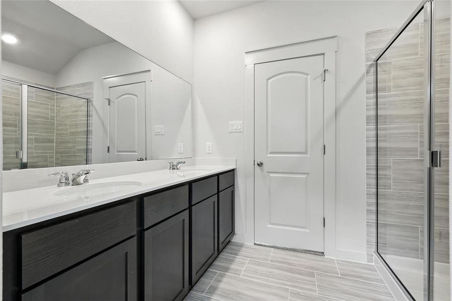 Full bathroom with a shower stall, double vanity, and lofted ceiling Full bathroom with a shower stall, double vanity, and lofted ceiling