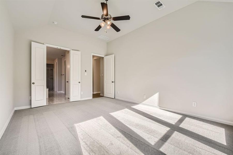 Unfurnished bedroom with light carpet, ceiling fan, and vaulted ceiling