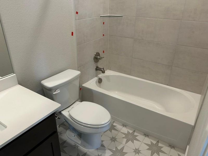 Full bath with a textured wall, vanity, and  shower combination