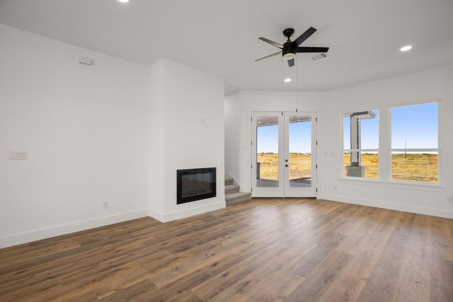 Bright, airy living space features a modern fireplace, durable wood flooring, and glass doors opening to the serene landscape. Bright, airy living space features a modern fireplace, durable wood flooring, and glass doors opening to the serene landscape.