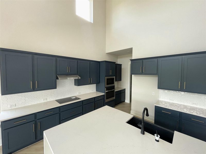 A well-lit kitchen presents rich cabinetry, sleek countertops, and high ceilings. A well-lit kitchen presents rich cabinetry, sleek countertops, and high ceilings.