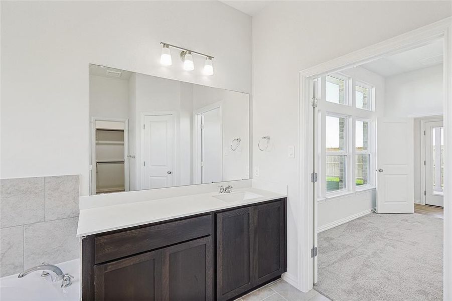 Bathroom featuring vanity, a tub to relax in, and a wealth of natural light