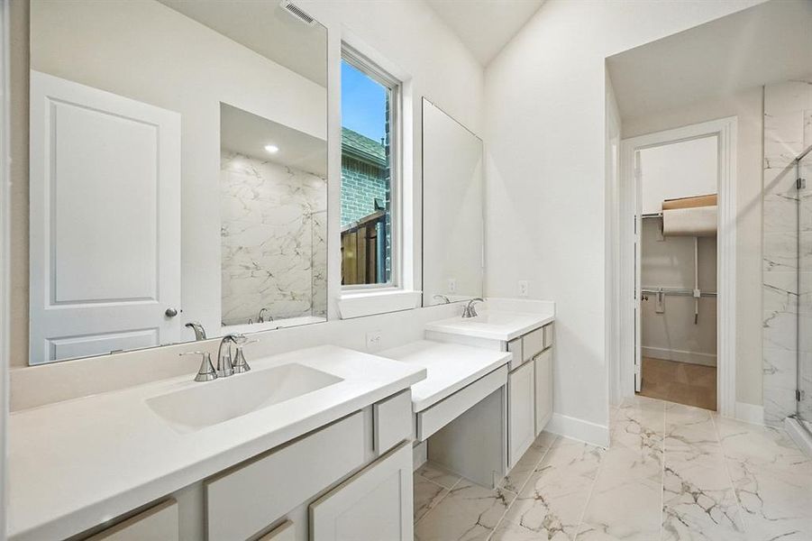 Bathroom with light marble finish flooring, a marble finish shower, two vanities, and a spacious closet Bathroom with light marble finish flooring, a marble finish shower, two vanities, and a spacious closet