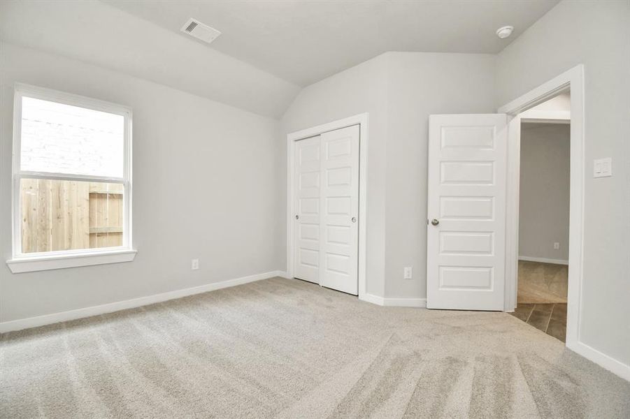 Secondary bedroom features plush carpeting, large windows that let in plenty of natural light, bright paint, and spacious closets.