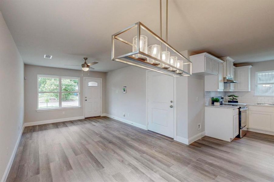 Kitchen with ceiling fan, white cabinets, stove, and light hardwood / wood-style flooring