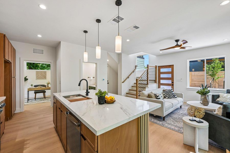 An open concept living area showcases a large kitchen island and natural wood look floors. An open concept living area showcases a large kitchen island and natural wood look floors.