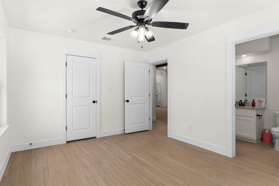 Unfurnished bedroom featuring light wood-type flooring, a ceiling fan, and ensuite bathroom