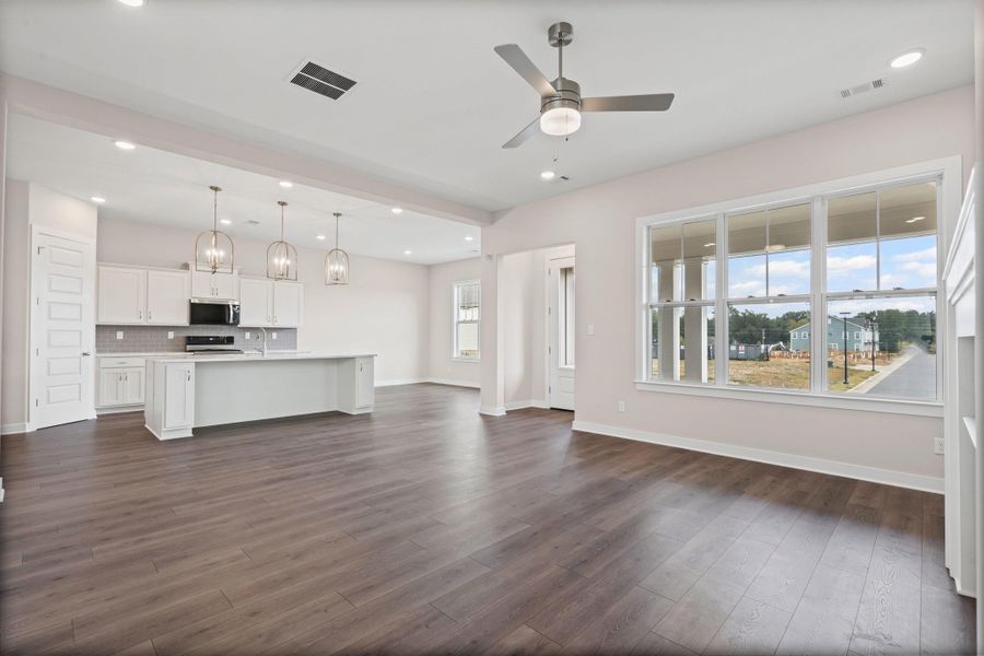 Unfurnished living room with healthy amount of natural light, recessed lighting, ceiling fan, and dark wood-type flooring