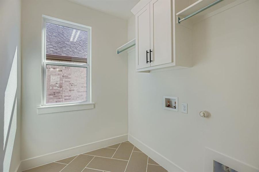 Washroom with cabinet space, light tile patterned flooring, hookup for a washing machine, and hookup for a gas dryer Washroom with cabinet space, light tile patterned flooring, hookup for a washing machine, and hookup for a gas dryer