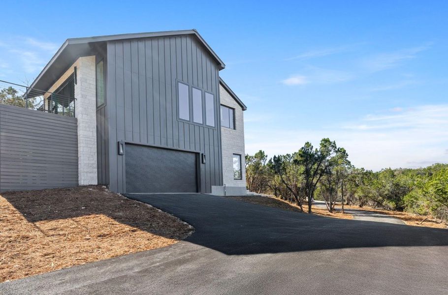 View of property exterior with aphalt driveway, board and batten siding, and a garage