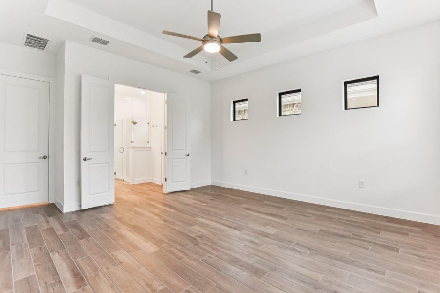 Unfurnished bedroom featuring a tray ceiling, light wood-type flooring, and a ceiling fan Unfurnished bedroom featuring a tray ceiling, light wood-type flooring, and a ceiling fan