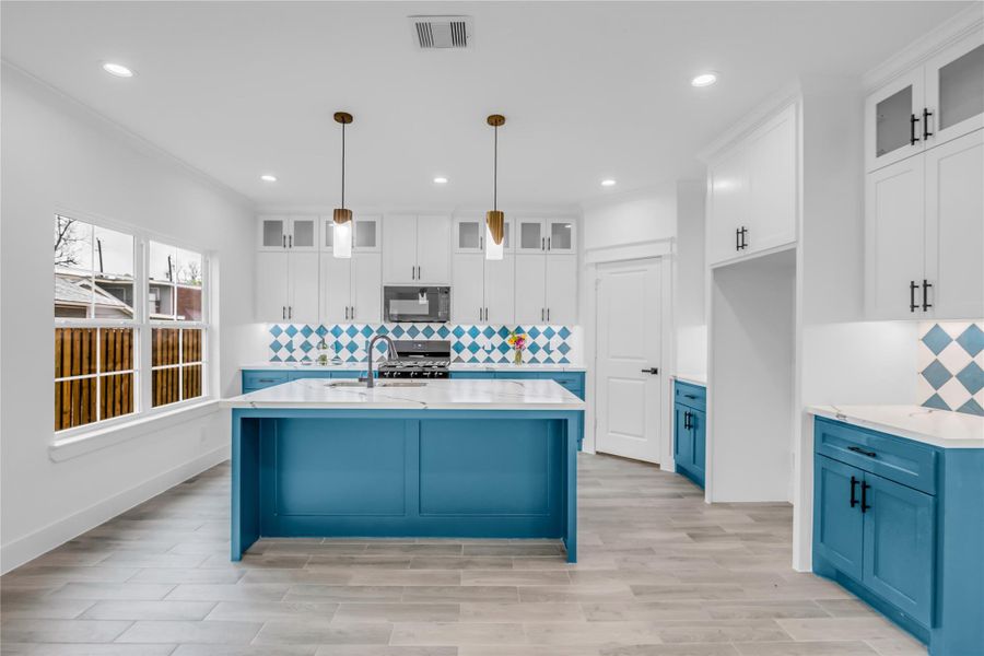 Discover a bright, modern kitchen with striking blue cabinetry, elegant white countertops, and eye-catching patterned backsplash, perfect for culinary creativity and entertaining.