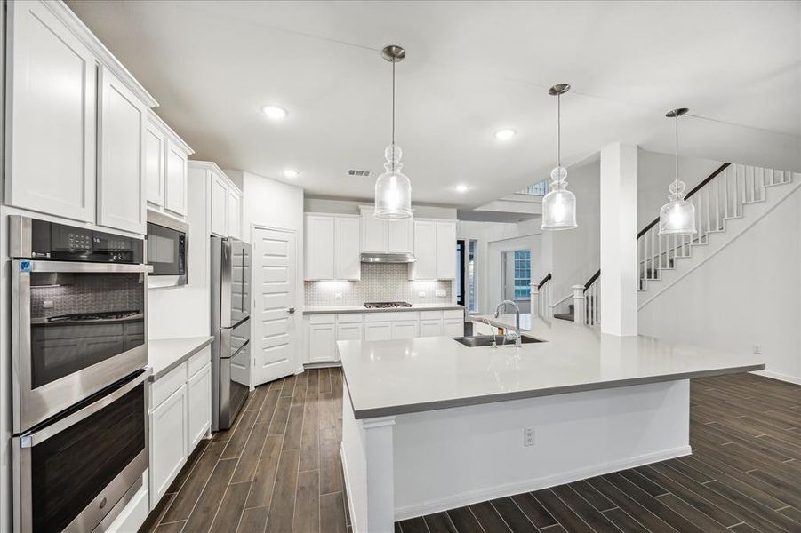 Step into the heart of the kitchen, where a large island takes center stage, complemented by stylish pendant lights overhead. This modern culinary space features double ovens, a sleek refrigerator, and ample storage, making it a chef's dream. With its thoughtful layout and elegant finishes, this kitchen is perfect for both everyday cooking and entertaining guests.