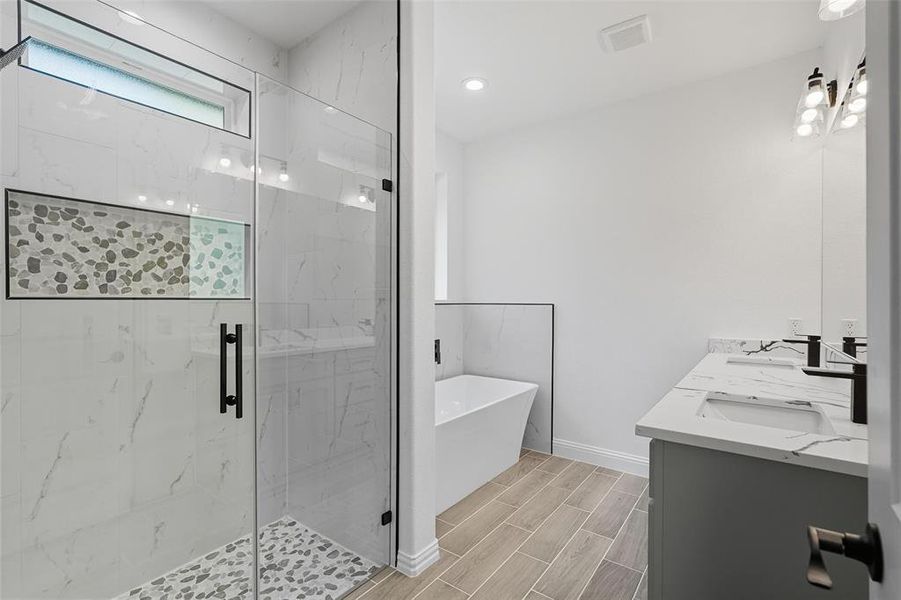 Bathroom featuring a soaking tub, a marble finish shower, double vanity, wood tiled floors, and recessed lighting Bathroom featuring a soaking tub, a marble finish shower, double vanity, wood tiled floors, and recessed lighting