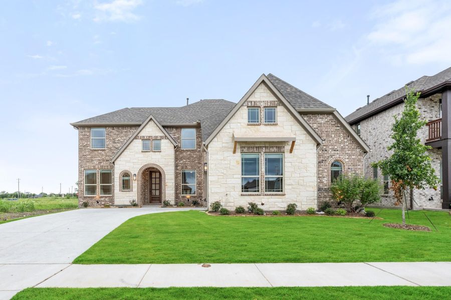Two-story home with brick and stone exterior, arched entry, and manicured front lawn Two-story home with brick and stone exterior, arched entry, and manicured front lawn