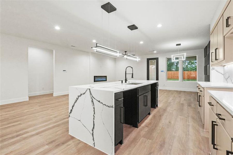 Kitchen featuring dark cabinetry, an island with sink, recessed lighting, light wood finished floors, and pendant lighting Kitchen featuring dark cabinetry, an island with sink, recessed lighting, light wood finished floors, and pendant lighting