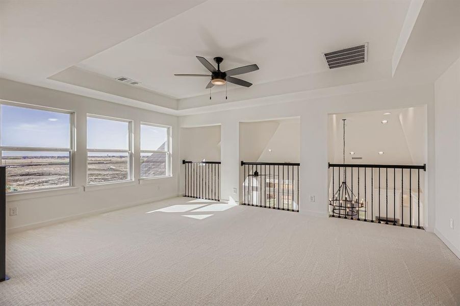 Carpeted spare room featuring a tray ceiling and ceiling fan Carpeted spare room featuring a tray ceiling and ceiling fan