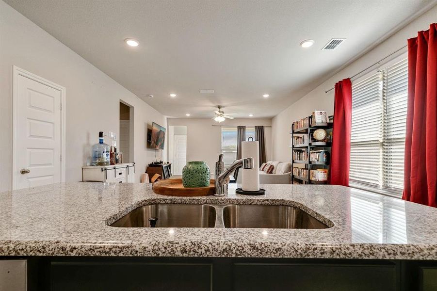 Kitchen with sink, ceiling fan, and light stone countertops