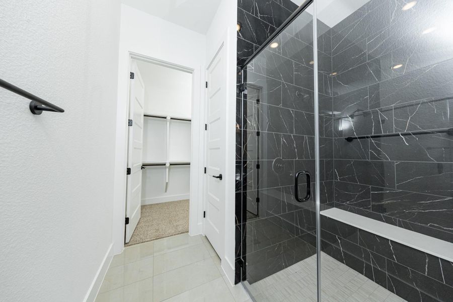 The walk-in shower includes a convenient, integrated white bench, offering comfort and a high-end, custom appearance.