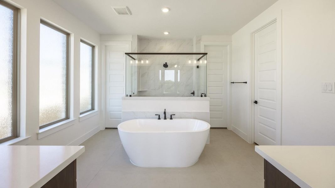 Bathroom featuring plenty of natural light, a marble finish shower, light tile patterned floors, a soaking tub, and recessed lighting Bathroom featuring plenty of natural light, a marble finish shower, light tile patterned floors, a soaking tub, and recessed lighting