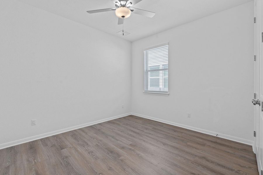 Unfurnished room with wood finished floors, a ceiling fan, and baseboards
