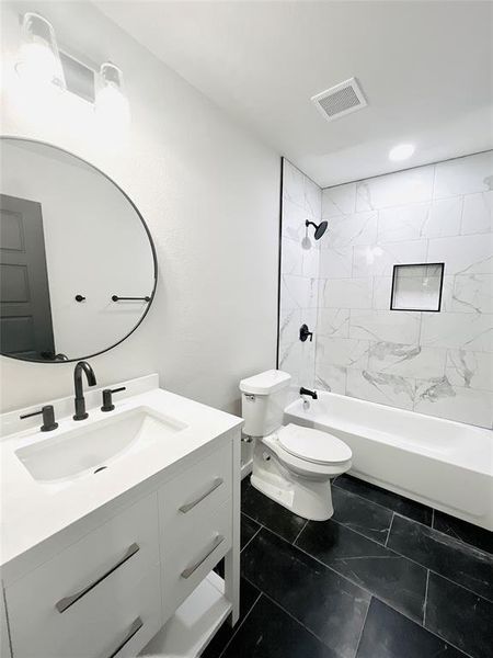 Full bathroom featuring vanity, tile patterned floors, tiled shower / bath, and toilet