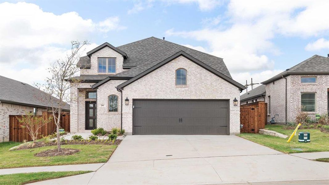 French country home featuring a garage and a front yard