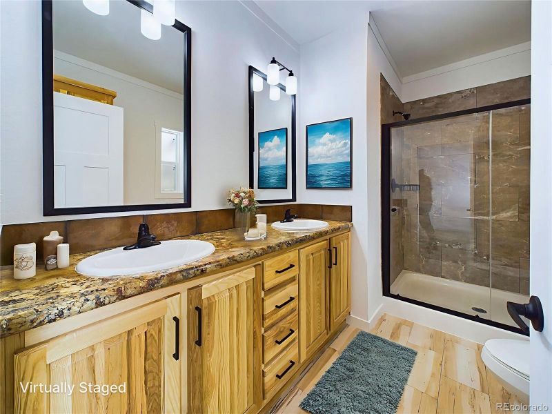 Bathroom featuring toilet, vanity, a shower